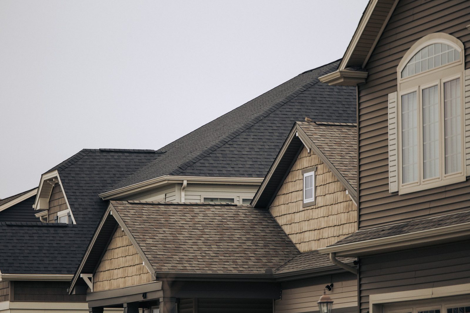 Close-up of a Castle Rock, Colorado home showing layered asphalt shingle roofs, gables, and cedar-shake dormers