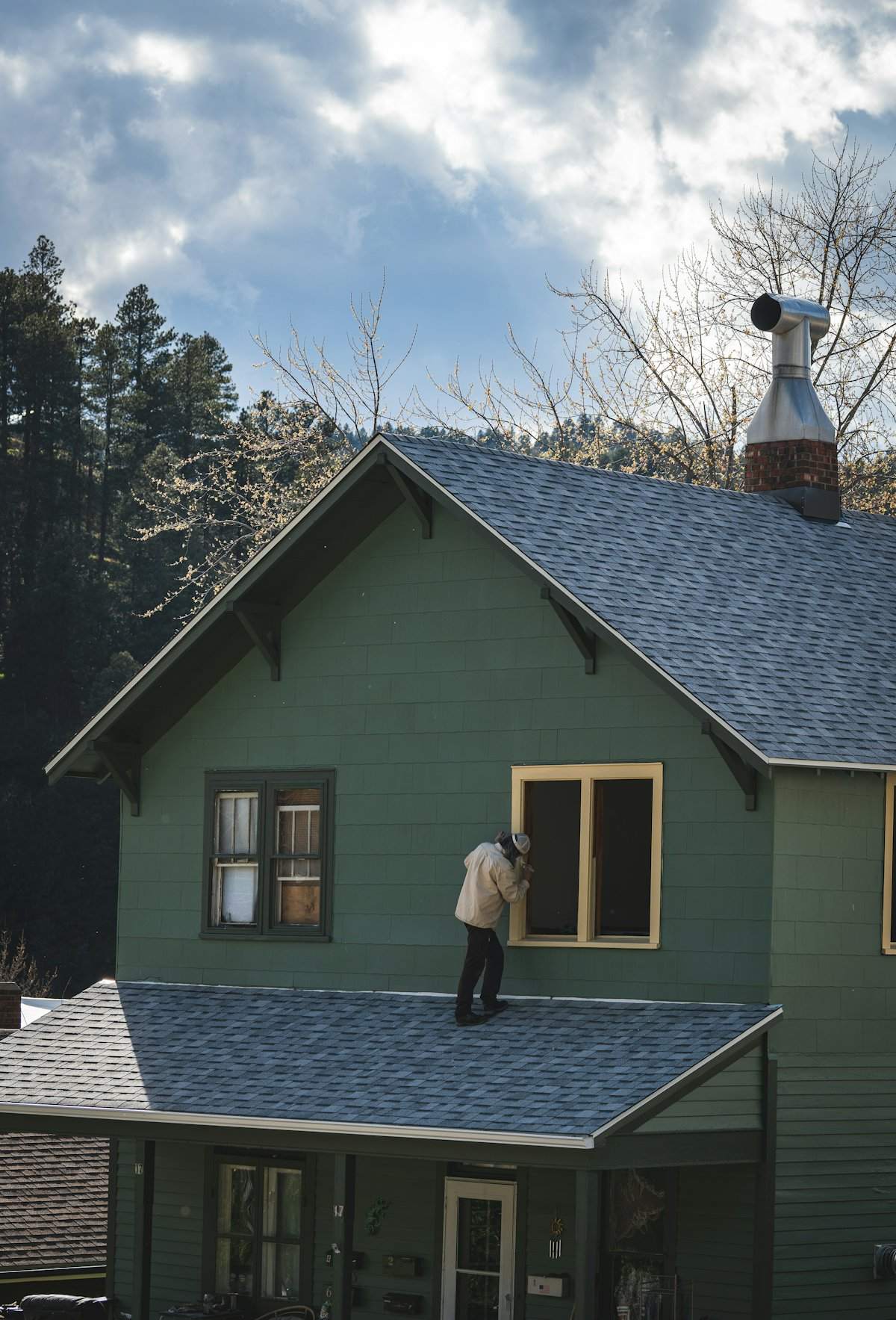 A painter working on the window trim of a two-story home