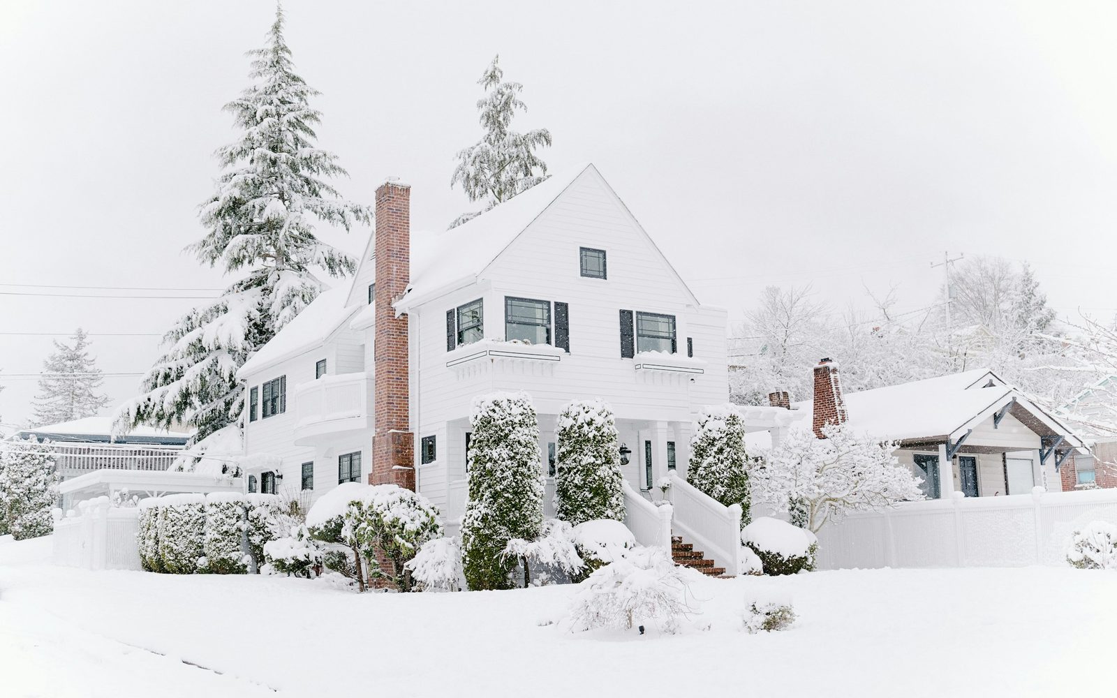Snow and ice built up along the eaves of a shingled roof on a Madison, Wisconsin home in winter